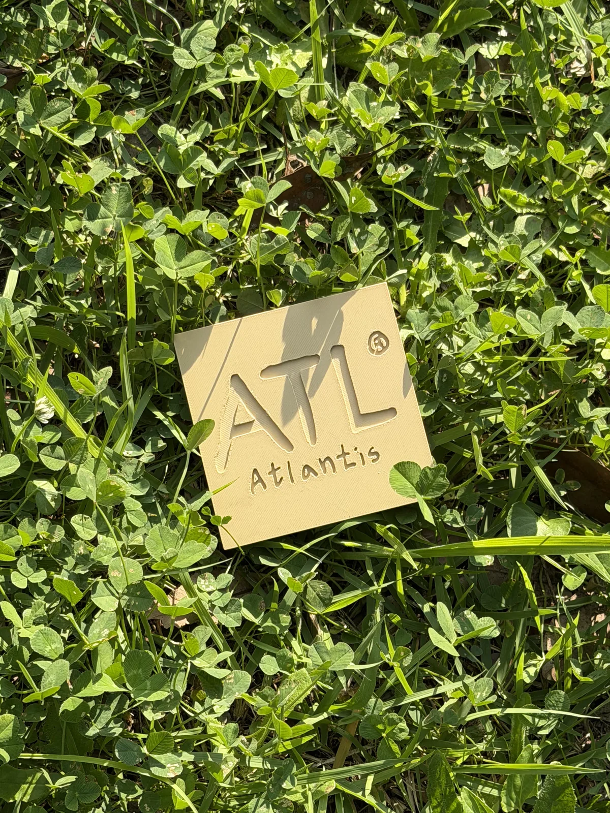 초록 풀 위에 놓인 ATL 로고 컵 받침대